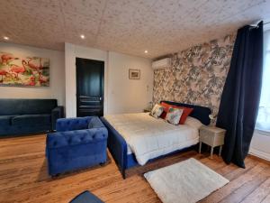 克卢尼LE MANOIR- CLUNY的一间卧室配有一张床和一张蓝色椅子