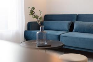 维里沙蒂隆The Blue and Gold Cocoon Appart hotel的一张蓝色的沙发和一张桌子上的玻璃花瓶