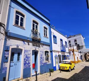 波尔蒂芒Charming Portuguese style apartment, for rent "Vida à Portuguesa", "Gaivota" Alojamento Local的停在蓝色建筑前面的黄色汽车