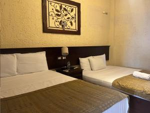 弗洛勒斯玛雅金塔酒店的酒店客房设有两张床,墙上挂着一张照片。