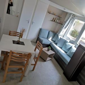维亚斯Mobil-Home Clos 14 à VIAS的客厅配有蓝色的沙发、桌子和椅子