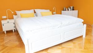SittersdorfB&B Gösselsdorfer Seeblick的卧室内的白色床,带有橙色的墙壁