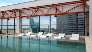 达拉斯16th FL Bold CozySuites with pool, gym, roof #1的一座带白色躺椅的游泳池