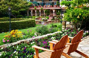 卡梅尔La Playa Hotel的两把木椅坐在鲜花盛开的花园内
