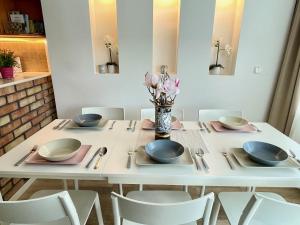 巴拉顿菲赖德Bonita Apartman & Garage的一张带椅子和盘子的白色桌子和花瓶