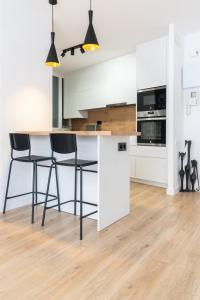 格拉诺列尔斯Apartment Granollers Up Live II的厨房配有白色橱柜和黑色吧台凳