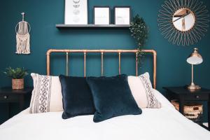 纽波特Commercial House, By Solace Stays的一间卧室拥有蓝色的墙壁,配有一张带黑色枕头的床。