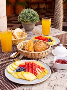 梅里达Viva Merida Hotel Boutique的一张桌子,上面放有水果盘、面包和橙汁