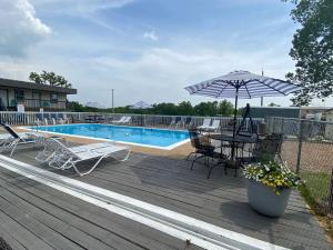奥沙克湖Rockwood Resort Motel的游泳池旁的甲板上配有桌子和遮阳伞