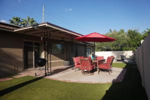 凤凰城3bdr Remodeled Scottsdale Desert Pool Oasis and Entertainment的庭院配有桌椅和遮阳伞。