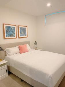 布里斯班Cosy and Stylish 1 BD Serviced Apt at SouthBank的卧室配有一张白色大床和粉红色枕头