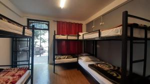 达兰萨拉Thrillomania Mcleodganj的客房设有三张双层床和一扇窗户。