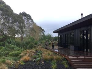 陶波Whakaipo Bay Cabin Retreat Taupo的田野旁的甲板房屋