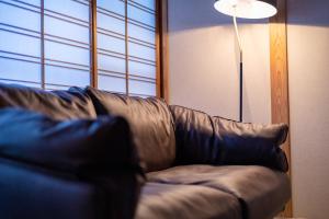 佐贺市Tsukasa Ryokan的客厅里一张棕色的皮沙发,配有灯