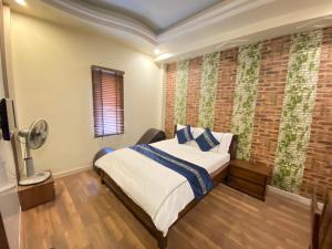 海防玫瑰酒店的一间卧室设有一张床和砖墙