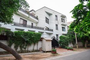 古尔冈BedChambers Serviced Apartments, Sushant Lok的街道旁的白色建筑,有栅栏