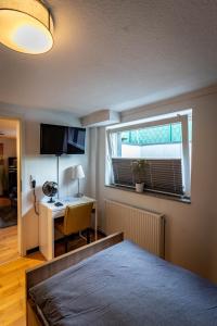 杜塞尔多夫Gemütliche 2-Zimmer Souterrain Wohnung的一间卧室配有一张床、一张书桌和一个窗户。