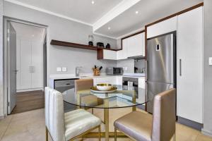 约翰内斯堡Executive and Spacious Apartments in Masingita Towers Sandton的厨房配有玻璃桌、椅子和冰箱
