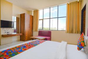 印多尔FabHotel Sukh Vilas的酒店客房设有一张床、一台电视和窗户。