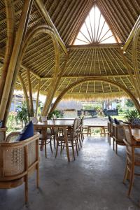 塔巴南Nadi Nature Resort - Adults Only的一间带桌椅和稻草屋顶的餐厅