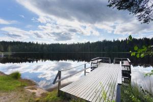 卡亚尼Lomaperkkiö Cottages的湖上木头码头,湖中云层