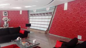 克雷塔罗瑞尔阿拉米达日克雷塔罗酒店的客厅设有红色的墙壁和黑色的沙发