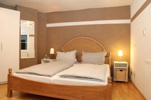 HerscheidFerienwohnung Vogler的一间卧室配有一张带白色床单和枕头的木制床。