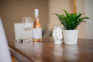 巴里Adriatico Home[Mare-Fiera-Centro]的一张木桌,上面放着一瓶葡萄酒和一株植物