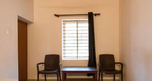 马迪凯里Westernghats Homestay的客房设有桌子、两把椅子和窗户。