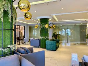 名古屋Grand Eska Hotel & Suites Batam的一个带沙发和大型绿色柱子的大堂