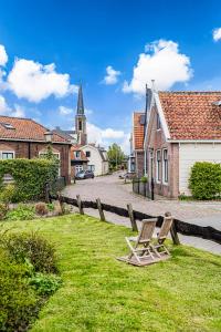 IlpendamAuthentic apartment in farmhouse near Amsterdam的村子里的一座带教堂的草地上的椅子
