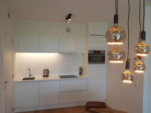 布兰肯贝赫The One - New luxury beachfront apartment的白色的厨房配有白色橱柜和灯