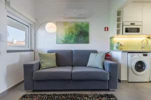 帕雷迪Green Oasis in Parede by LovelyStay的客厅配有蓝色沙发和洗衣机
