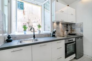 科孚镇Passaggio studio的厨房配有白色橱柜、水槽和窗户。