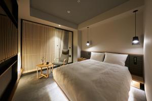 大阪Hotel Resol Trinity Osaka的卧室配有一张白色大床和一把椅子