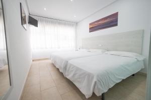 擞莫擞莫皮纳尔冲浪酒店的一间白色卧室,配有两张床和窗户