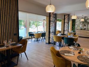 穆昂萨尔图Urban Style Cannes Mouans-Sartoux - Piscine Extérieure - Parking Gratuit的餐厅设有木桌、椅子和窗户。
