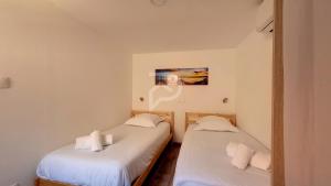 埃圭斯海姆Le Nature d'Eguisheim的白色墙壁客房中的两张单人床
