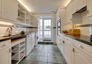 森嫩Flora Belle Cottage的厨房配有白色橱柜和瓷砖地板。