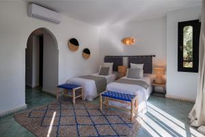 马拉喀什Villa Al Assala Palmeraie的一间卧室配有两张床和两把椅子,铺有地毯。