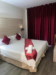 罗列特海岸诺莱酒店的卧室配有带红色枕头的大型白色床