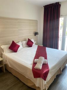 罗列特海岸诺莱酒店的一间卧室配有一张带红色和白色枕头的大床