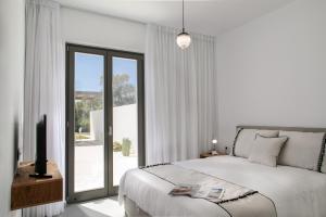 纳克索乔拉STONE VILLA NAXOS的白色卧室设有床和滑动玻璃门