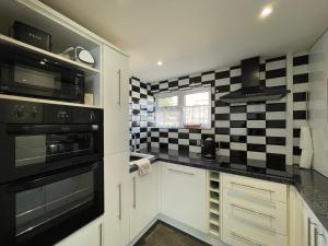 佩文西Quaint 2 Bed Village Retreat的厨房的墙壁上铺有黑白格子瓷砖。