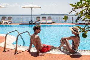 加尔多内-里维耶拉佛罗里达别墅酒店套房&套房公寓的坐在游泳池旁的男人和女人