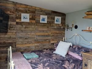 赫尔斯顿Rhubarb Hut, set in the beautiful Cornish Countryside的一间卧室配有木墙和一张床