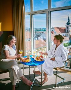 布尔诺Hotel Avion - National Cultural Monument - ICONIC HOUSES ORG的两个女人坐在桌子上,一边吃着酒