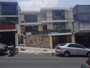 危地马拉Hospedaje Via 7的停在大楼前的汽车和摩托车