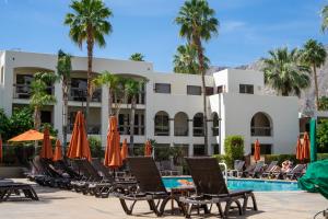 棕榈泉棕榈山Spa度假酒店的游泳池旁的酒店拥有椅子和遮阳伞