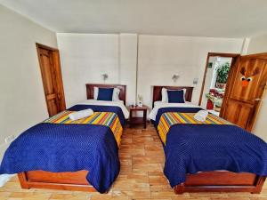基多Casa CarpeDM的一间卧室配有两张蓝色和黄色的毯子